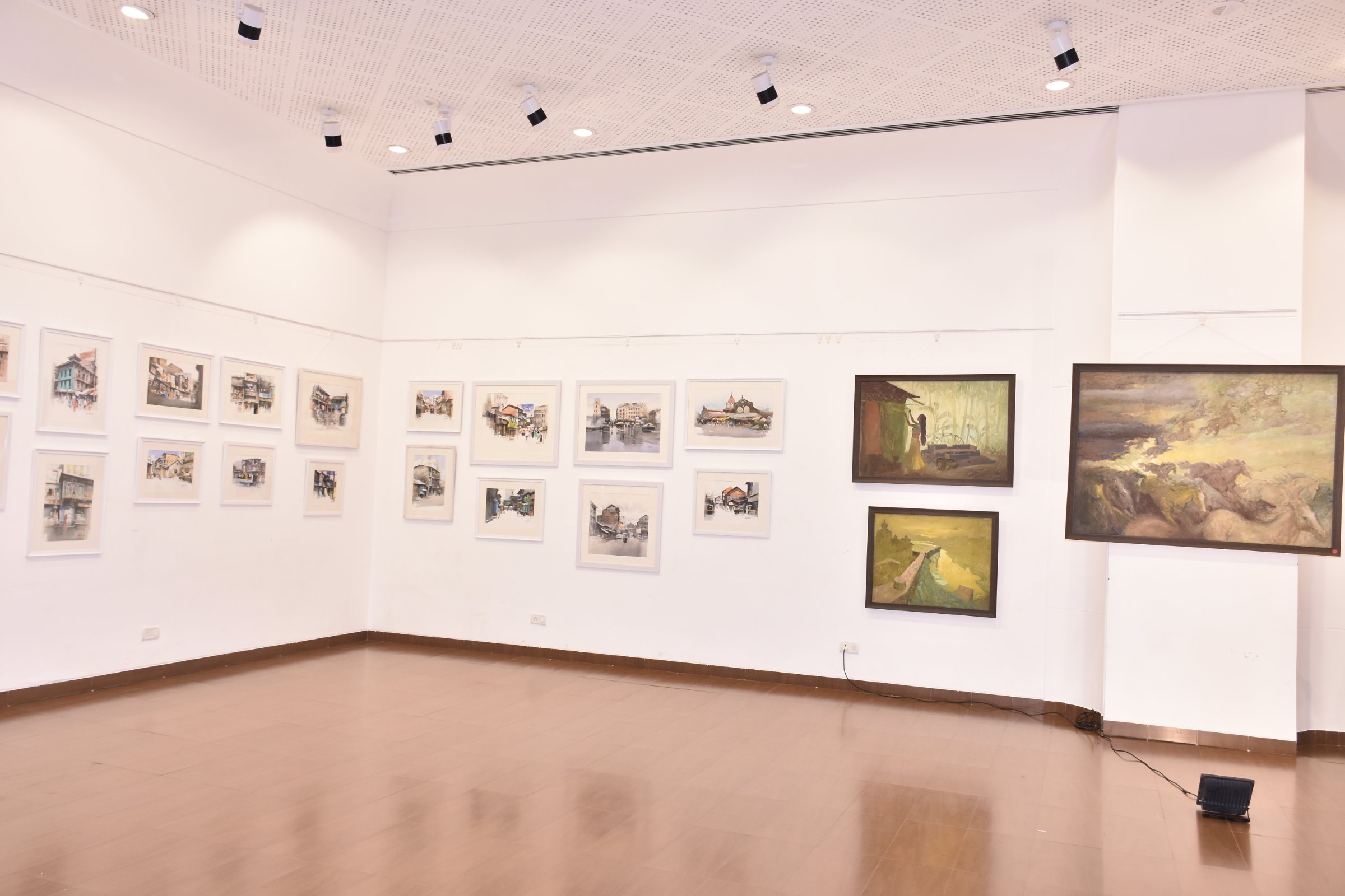 Corner view of the hall - watercolour street scenes on the left wall, Pratap Mulick’s oils on the right