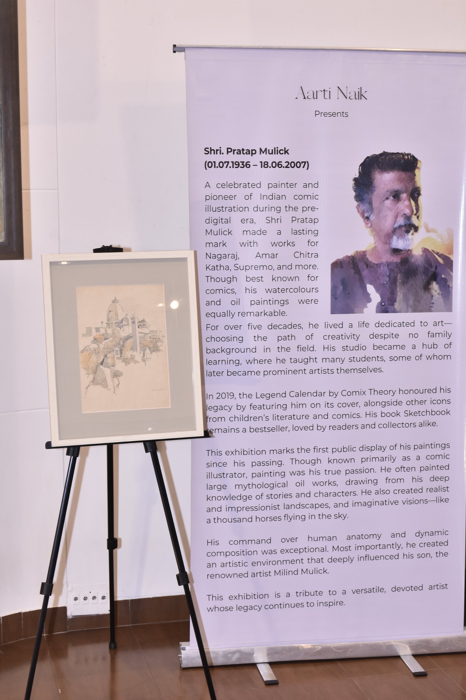 The About Pratap Mulick standee beside a framed pencil sketch on an easel