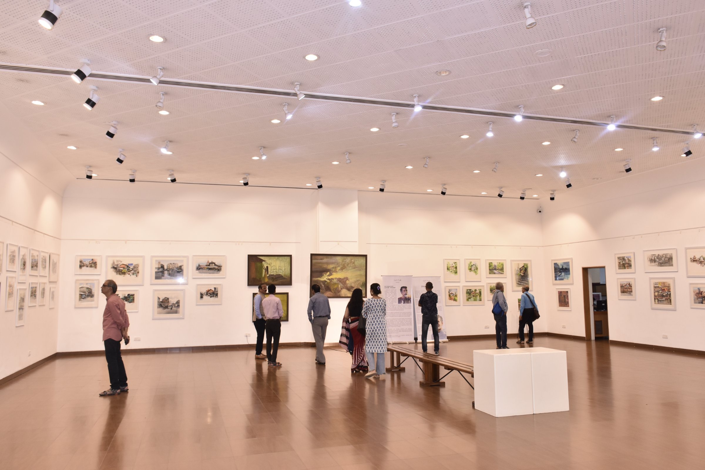 Opening view - visitors moving through the full hall of watercolours and oils