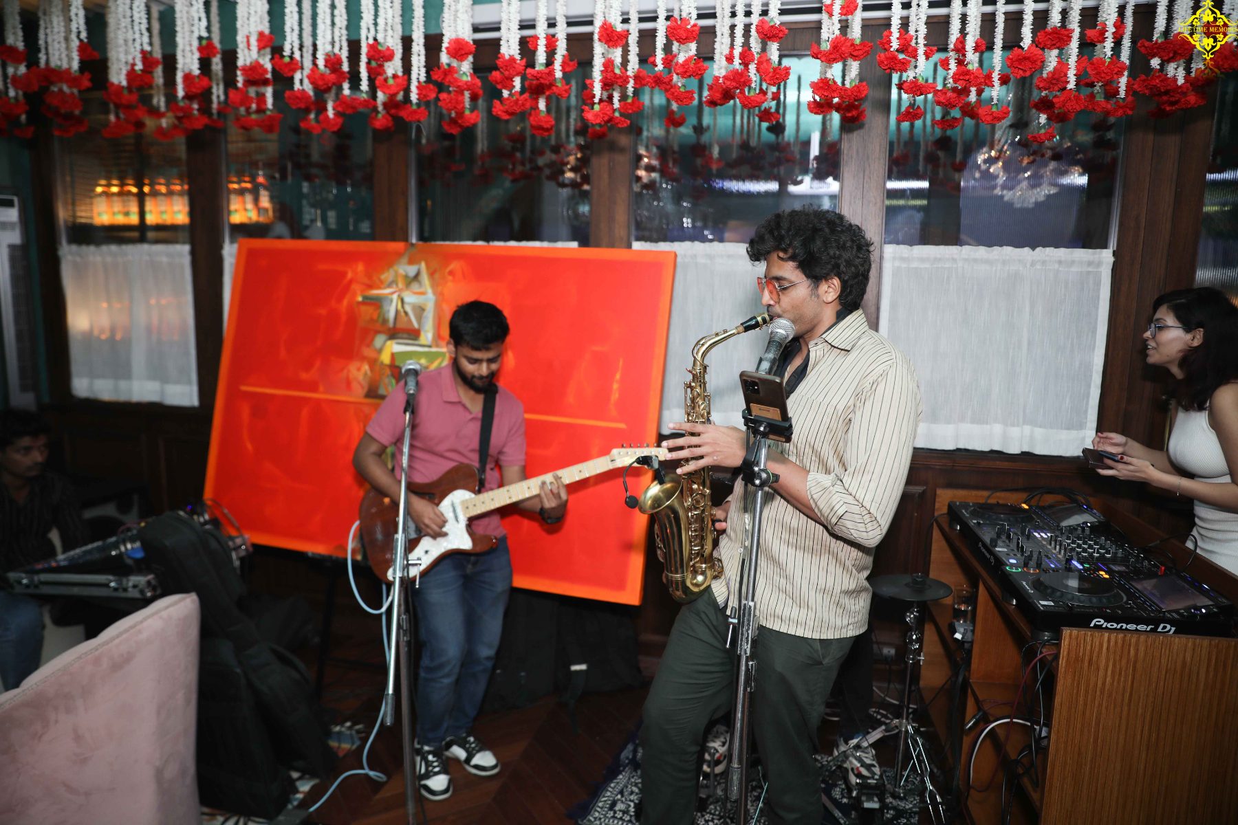 Live saxophone and guitar beneath carnation garlands