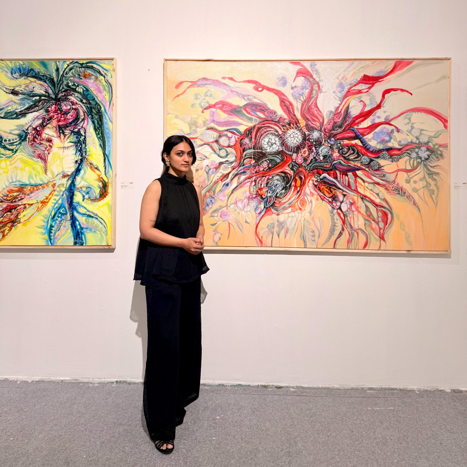 An artist standing between her two finished canvases